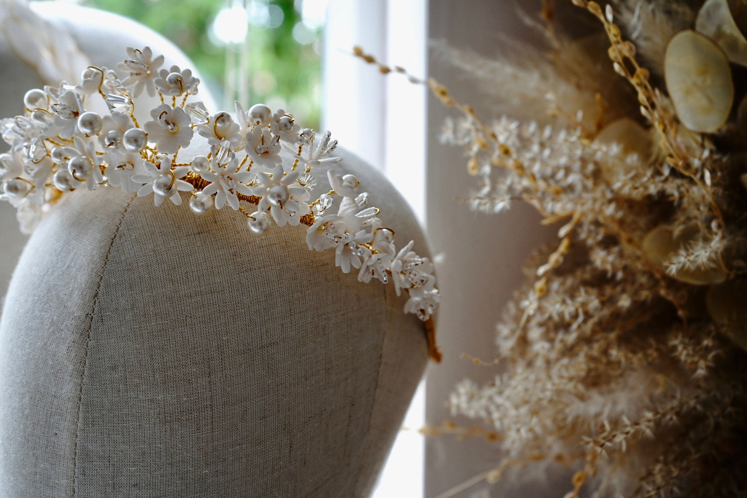 Decorative bridal headband with flowers and pearls on a mannequin head with a blurred background