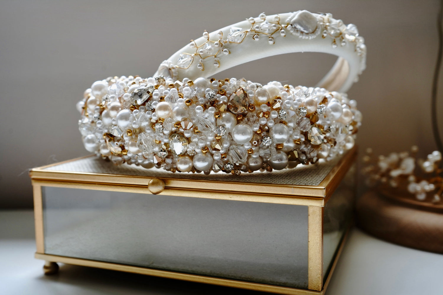 Decorative box with pearl and gold embellishments on a reflective surface.